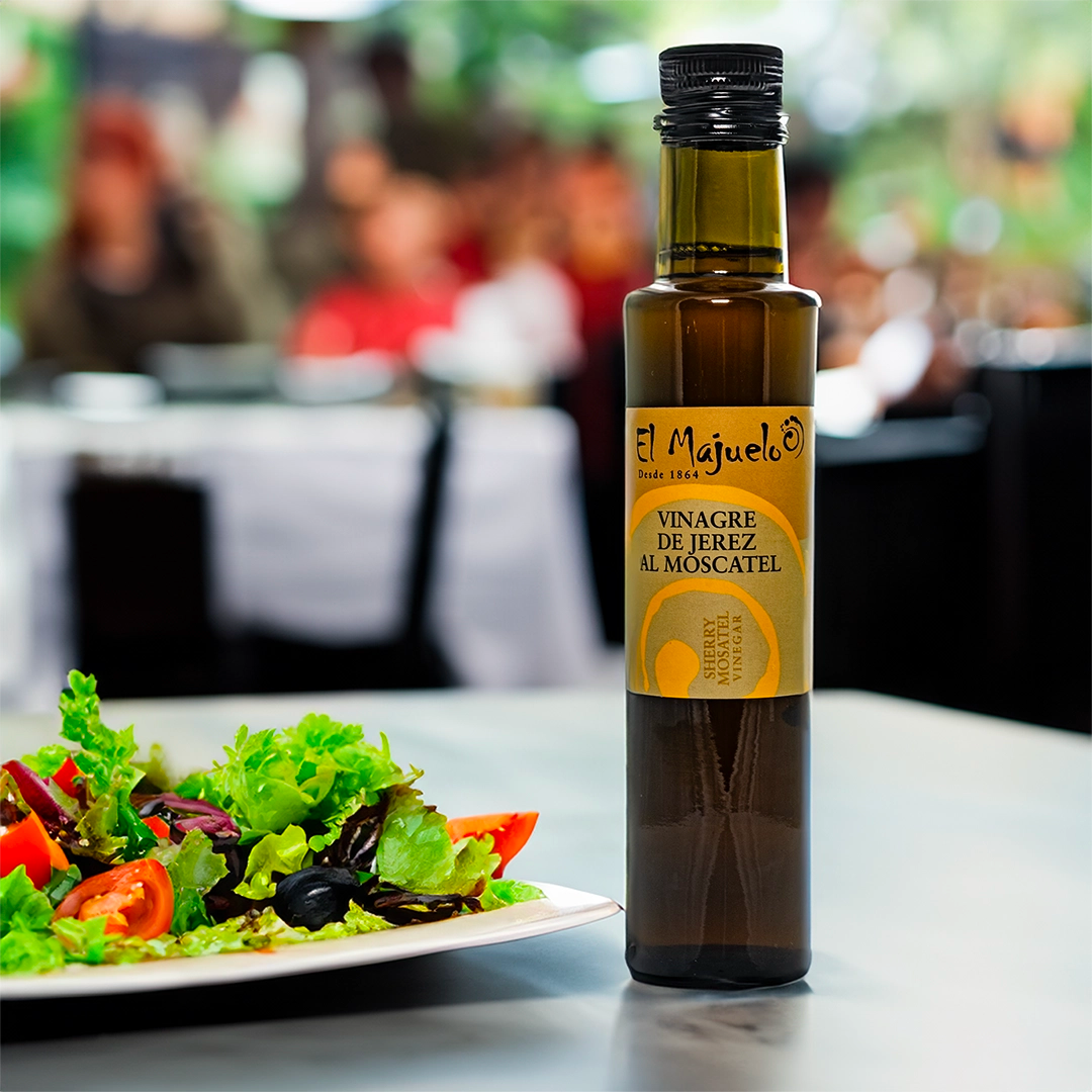a lifestyle image of the El Majuelo oil in a restaurant, the bottle in the image is next to a salad 