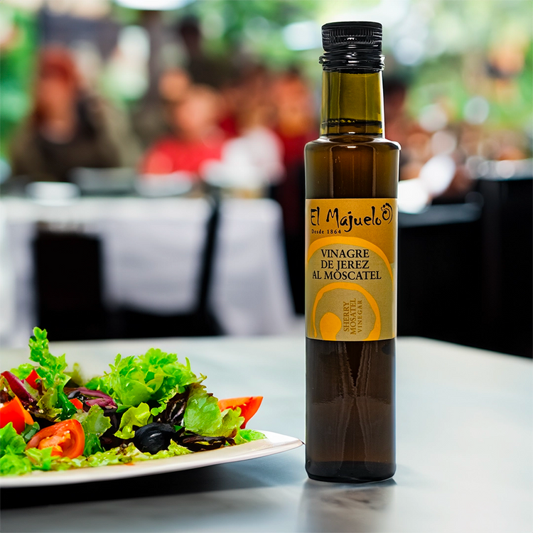 a lifestyle image of the El Majuelo oil in a restaurant, the bottle in the image is next to a salad 