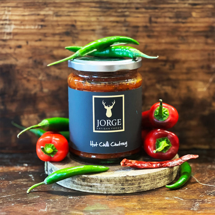 Jar of Jorge Hot Chilli Chutney with red chillies  on a table